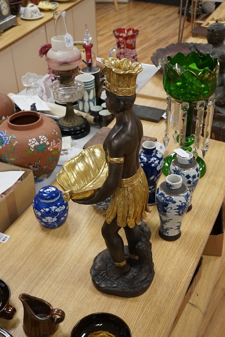 A gilded resin model of an Nubian boy holding a shell and wearing a crown, 65cm high.